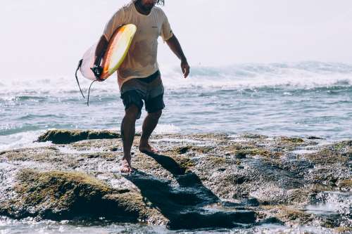 Man Carrying Surfboard Emerges From Ocean Waves Photo