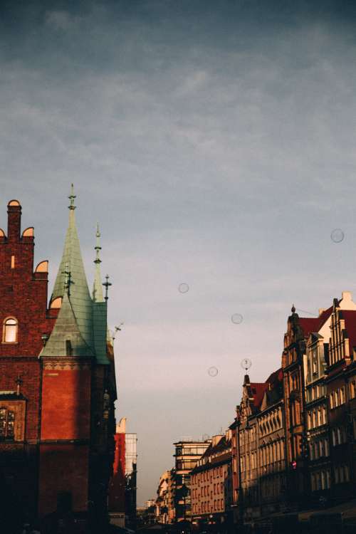 Soap Bubbles Float Over Red Brick Spires Of A Town Photo