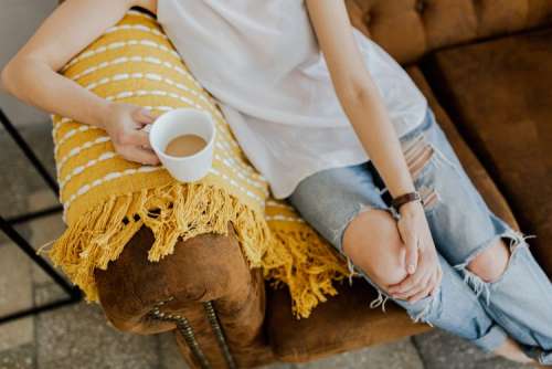 A woman with a cup of coffee reads a book