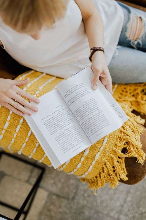 A woman with a cup of coffee reads a book