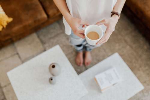 A woman with a cup of coffee reads a book