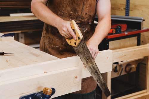 Woodworker Using Handsaw In Workshop Photo