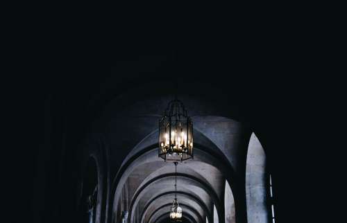 A Glass Lantern Of Candles In A Corridor Of Arches Photo