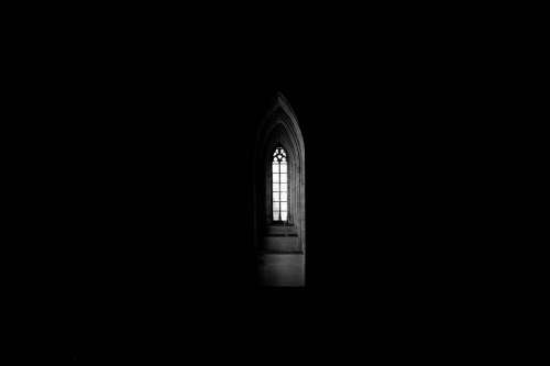 A Gothic Church Window Spills Light Into Interior Darkness Photo