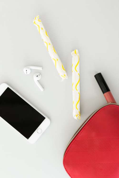 A Red Purse Spills Feminine Products Onto A Table Photo