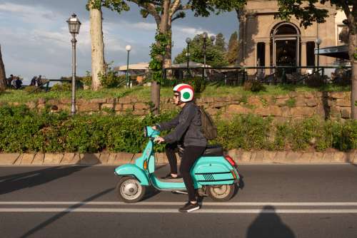 A Woman On A Turquoise Moped On A Highway Photo