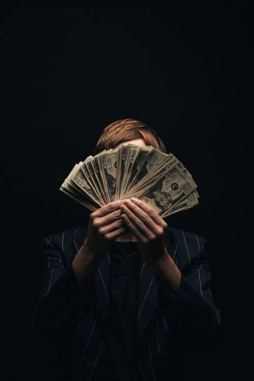 Person Holds Money In Front Of Face Photo