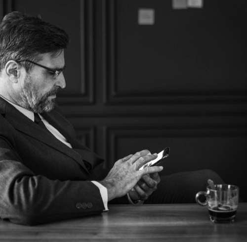 Black and white of a bearded businessman looking at his mobile phone