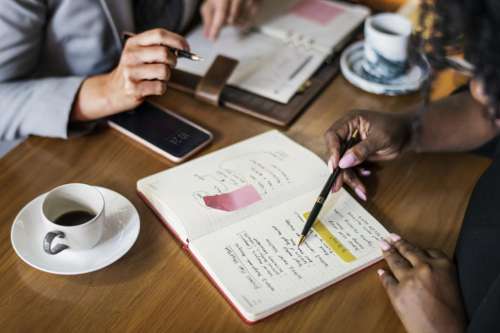 Anonymous womans hand taking notes at a cafe table