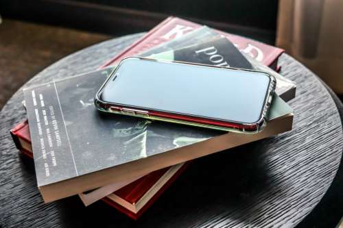 Phone on top of books, on a table