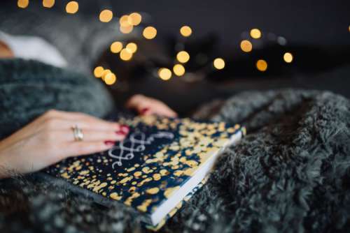 Young woman at home reading Hygge book and drinking