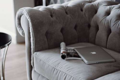 Elegant grey sofa with a laptop, an iPhone and a magazine