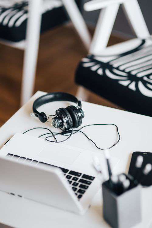 White laptop with smartphone and headphones