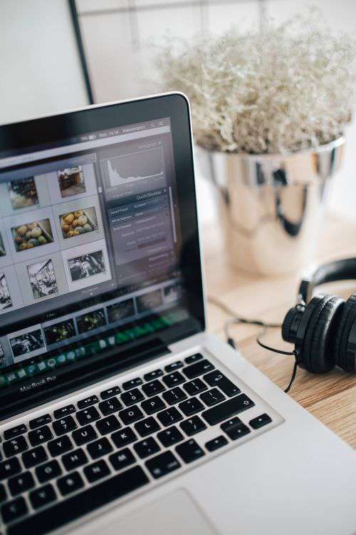 MacBook Pro with headphones on a wooden desk