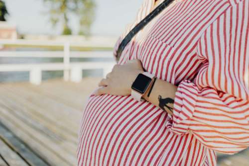 A pregnant woman with a smartwatch on her hand