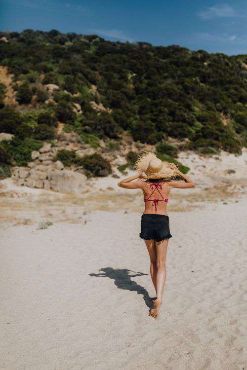 Beautiful woman in pink swimsuit and black shorts on the beach