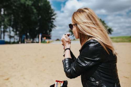 Young woman wearing a leather jacket and sunglasses on the beach