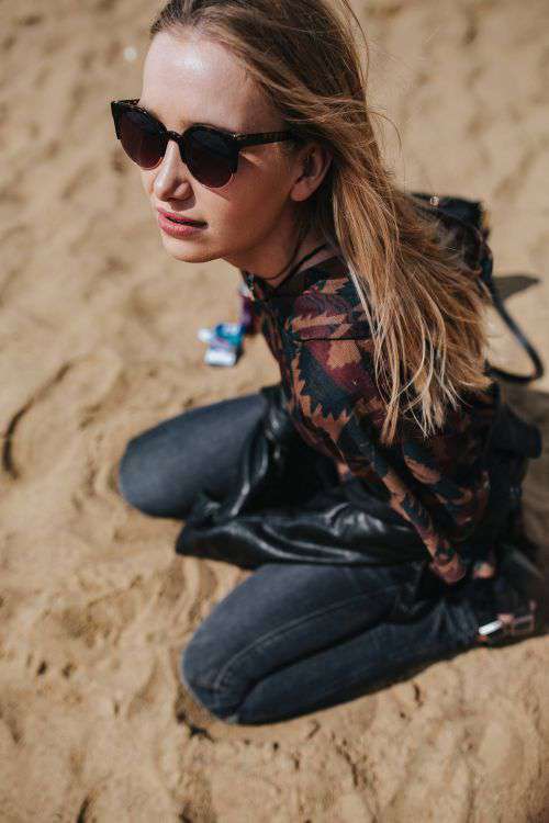 Young woman wearing a leather jacket and sunglasses on the beach