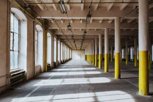 Interior of an abandoned building hall with yellow pillars