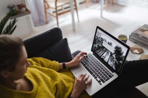 Young woman sitting on the sofa and working on her laptop