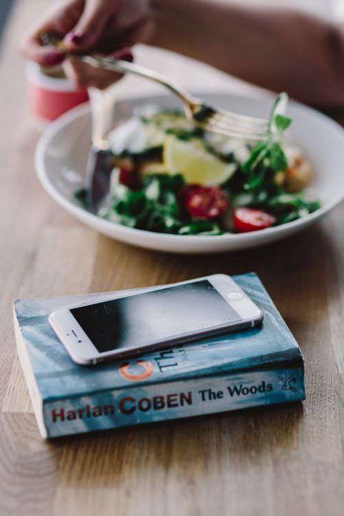 Woman eating breakfast and reading a book