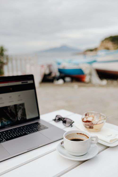Working with a laptop by the sea. Cup of coffee and delicious tiramisu, Marina di Puolo, Italy