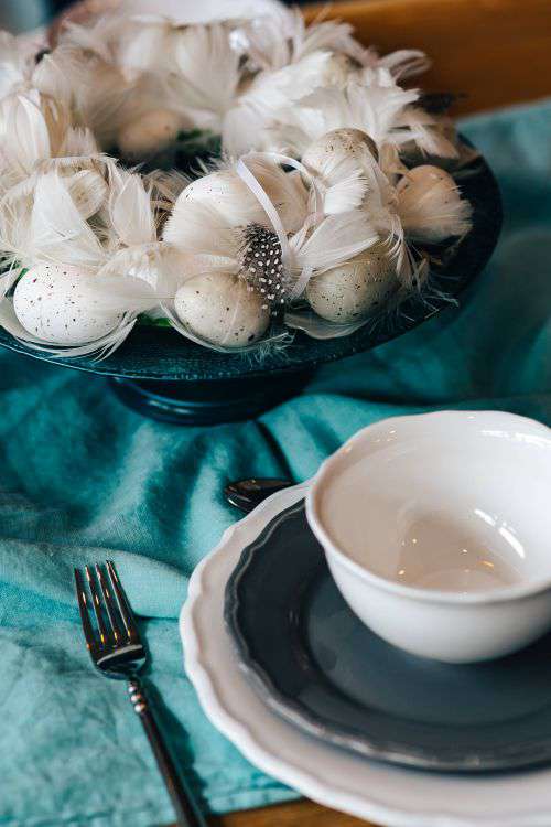 Fancy restaurant dinner table decorated with quail eggs and feathers