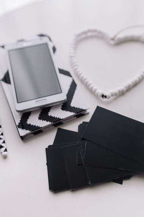 Black-and-white notebook and a white smartphone with various items