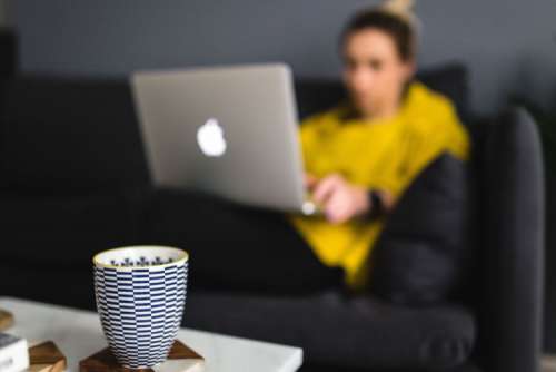 Young woman sitting on the sofa and working on her laptop
