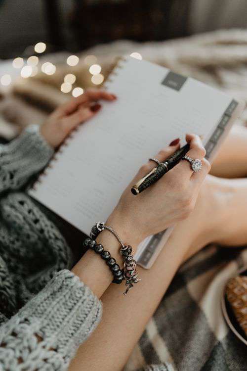 Writing in a notebook lying in bed, with coffee, candles, and gingerbreads