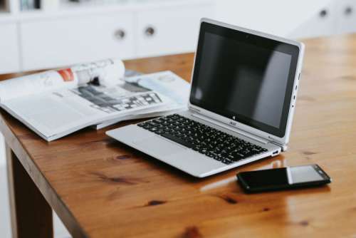 Silver laptop with various items on a table