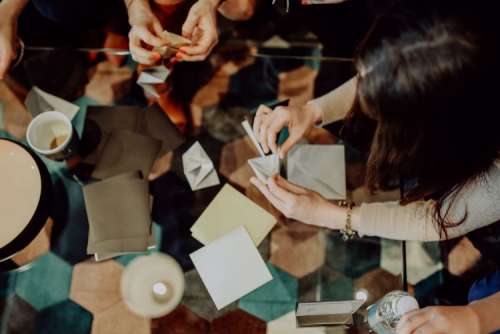 Women folding sheet of paper while making origami