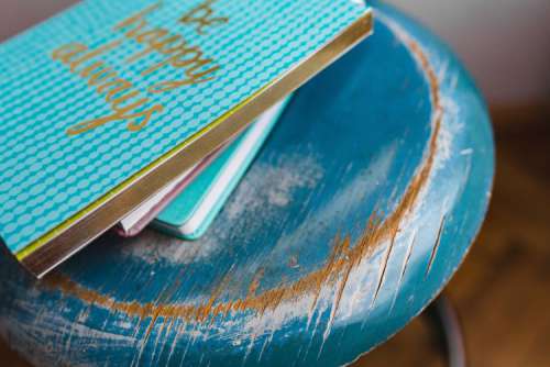 Blue notebooks and a camera on a blue wooden stool