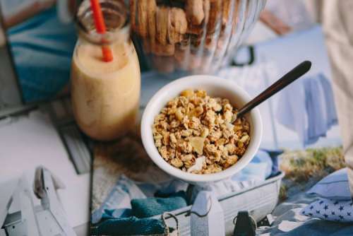 Jar full of walnuts with a fresh healthy shake and musli in a bowl