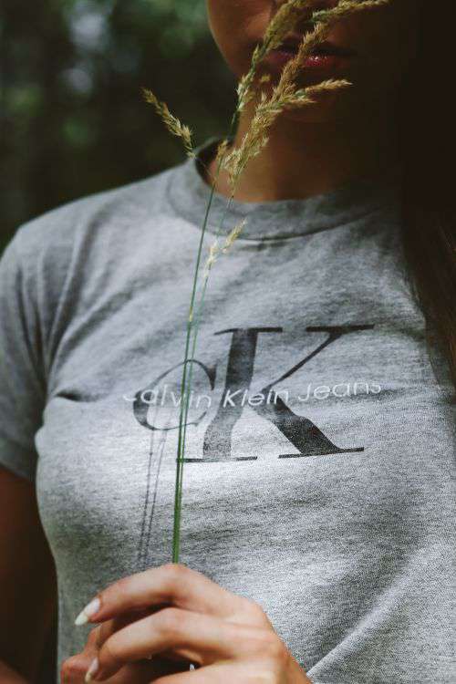 Woman in a grey crop top shirt holding wheat