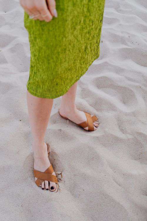 A woman in a green dress on the beach with white sunglasses