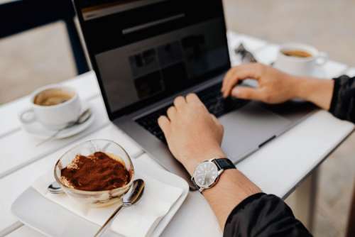 Working with a laptop by the sea. Cup of coffee and delicious tiramisu, Marina di Puolo, Italy