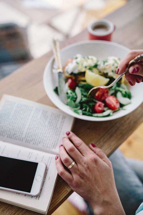 Woman eating breakfast and reading a book