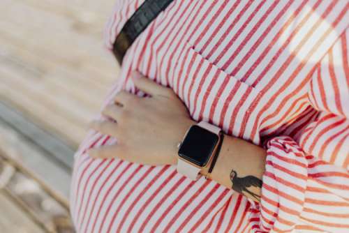 A pregnant woman with a smartwatch on her hand