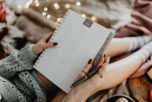 Writing in a notebook lying in bed, with coffee, candles, and gingerbreads