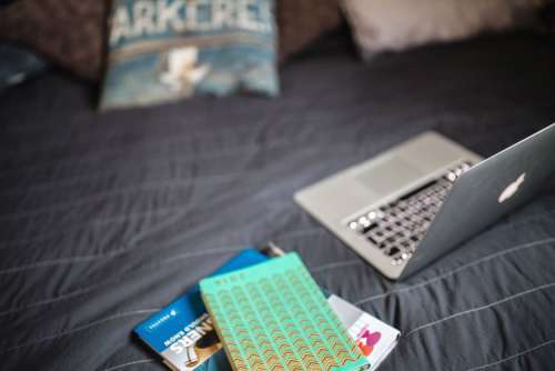Laptop with books on a bed