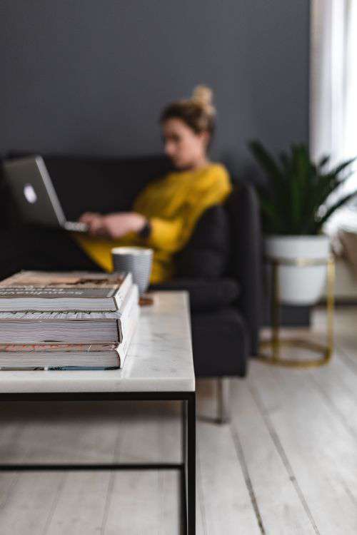 Young woman sitting on the sofa and working on her laptop