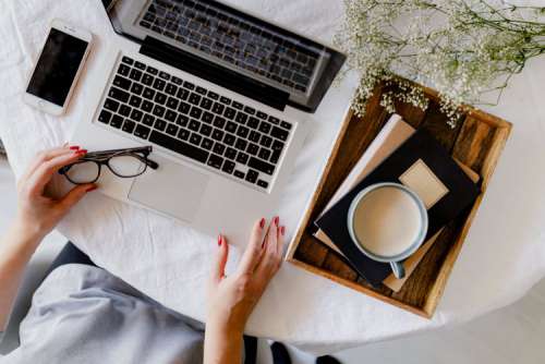 A woman works at a desk with a laptop and a cup of coffee