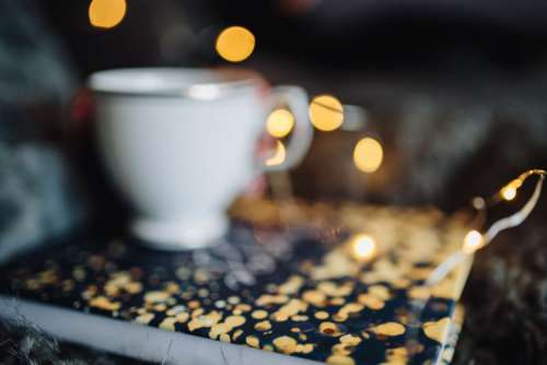 Young woman at home reading Hygge book and drinking