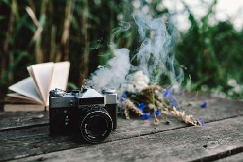 Colorful smoke bomb, book and vintage camera