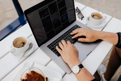 Working with a laptop by the sea. Cup of coffee and delicious tiramisu, Marina di Puolo, Italy