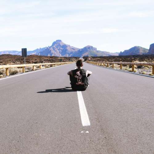 Man sitting in empty road Free Photo