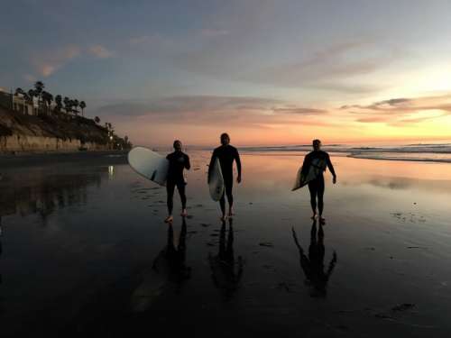 Surfers leaving the beach at sunset after surfing . 