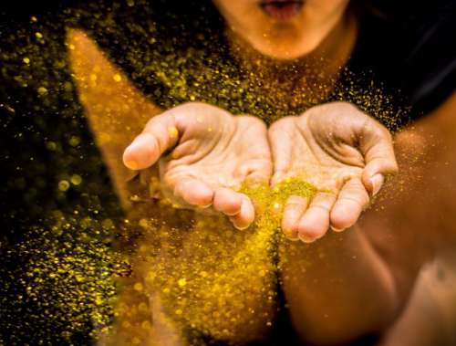 Girl blowing gold confetti / glitter 

