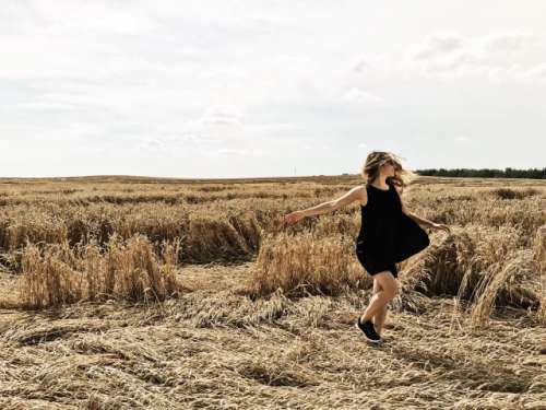 Happy young woman dancing in field.